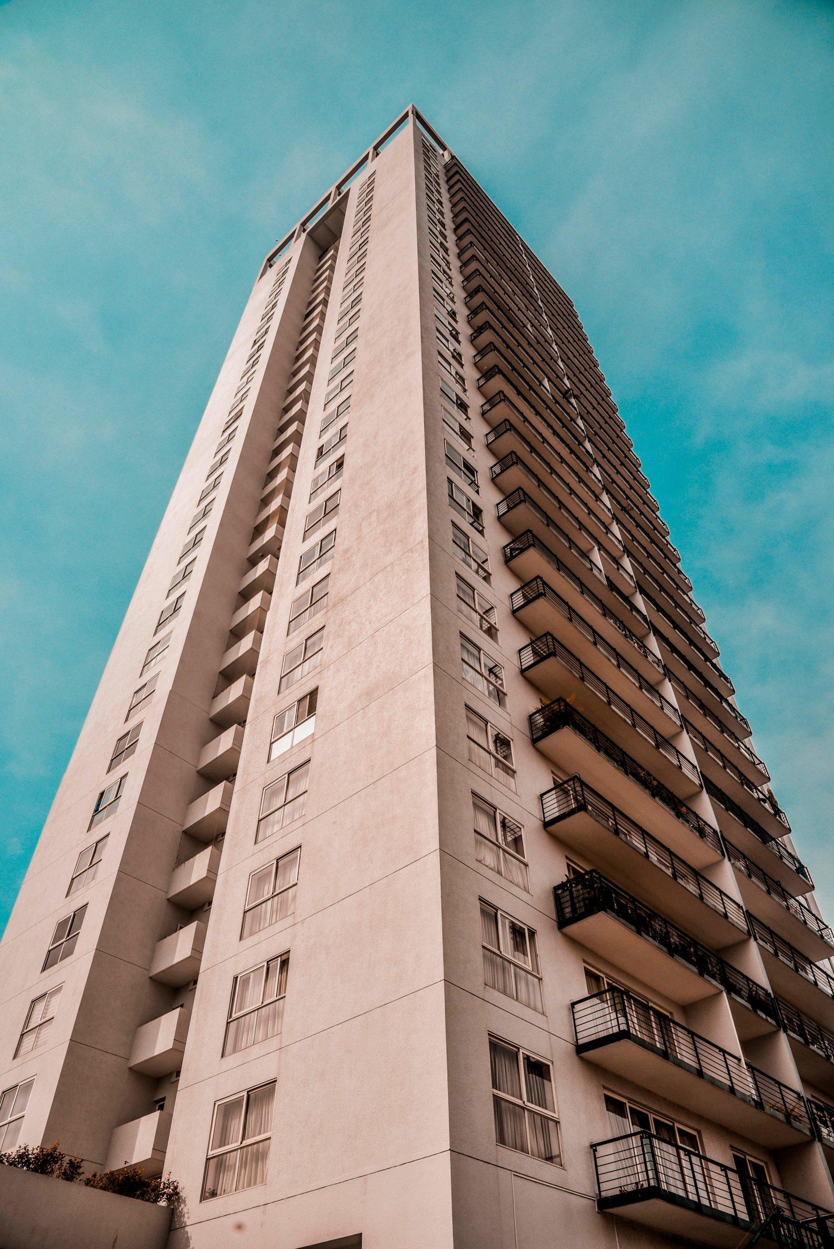 A low-angle view of a modern high-rise building with a clear blue sky backdrop.